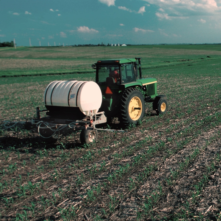 A tractor applying nutrients  to a crop field
