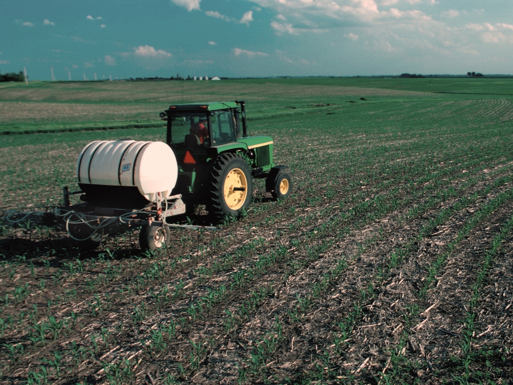 A tractor applying fertilizer to a crop field