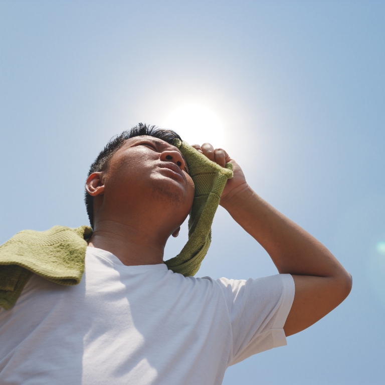 A person wiping sweat off in the heat